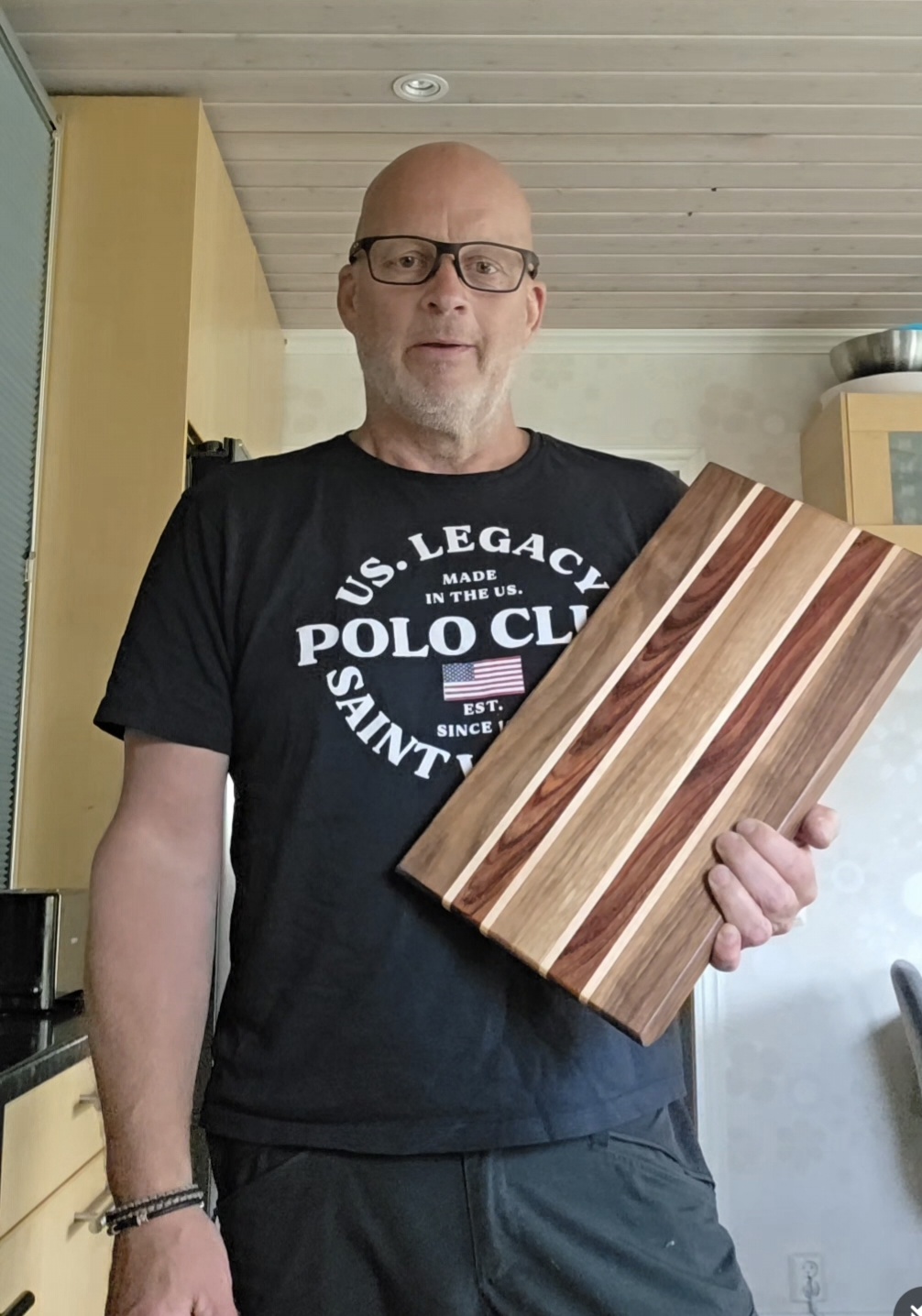Hantverkaren håller upp en handgjord skärbräda i flera träslag